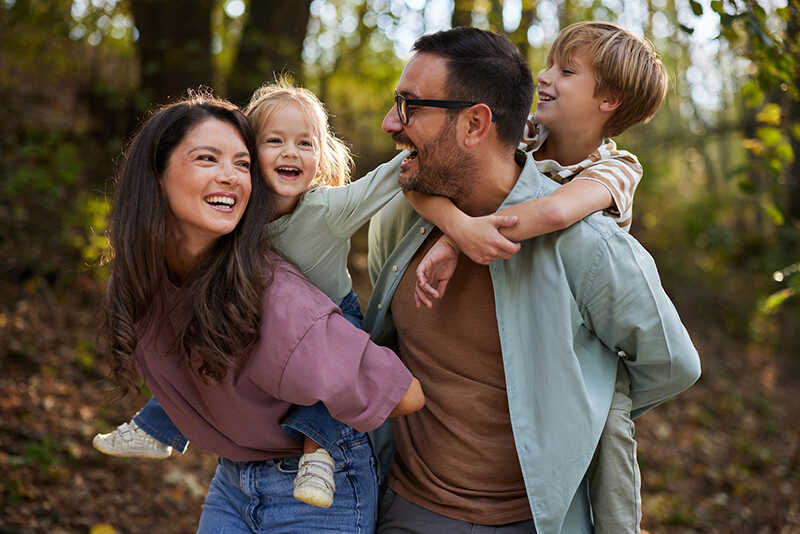 Happy family piggybacking during spring day at the park.