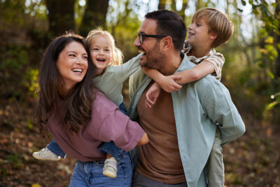 Happy family piggybacking during spring day at the park.