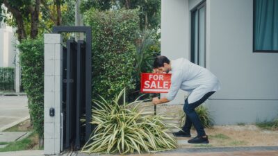 man putting for sale sign