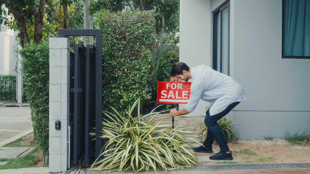 man putting for sale sign